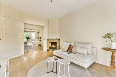 Hafif renk paleti, modern mobilyalar ve sıcak ve davetkar bir atmosfer yaratan doğal elementlerin yer aldığı şık bir minimalist oturma odası..