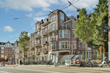 Bisikletlerle dolu kalabalık bir cadde boyunca balkonların ve ağaçların yer aldığı kentsel mimarinin resimli bir görüntüsü..