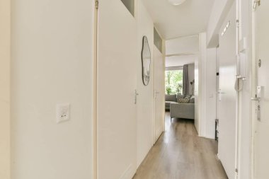 Geniş ve aydınlık modern bir iç koridor, rahat bir yaşam alanına açılıyor. Tasarım pencereye doğru akan temiz çizgiler ve doğal ışık içerir..