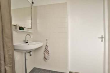 Zarif, çağdaş banyo tasarımı, şık bir ayna ve minimalist dekoru olan temiz bir lavabo. Tarafsız tonlar geniş hissi arttırır..