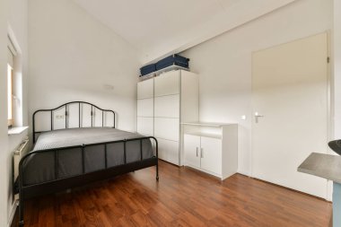 Siyah metal bir yatak odası, ahşap döşeme ve odanın ferah havasını arttıran minimalist mobilyalar..