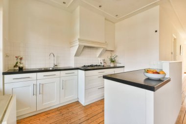 Beyaz dolap, minimalist tasarım ve ferah ve işlevselliği ön plana çıkaran ahşap döşeme ile gösterişli ve modern bir mutfak..