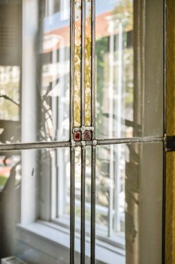 Geometrik desenleri ve canlı renkleri olan, güneş ışığını güzel yansıtan ve iç mekandaki ambiyansı geliştiren karmaşık bir vitray..