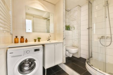 Gösterişli ve modern bir banyo. Çamaşır makinesi, duş ve şık bir dekor. Küçük bir alanda işlevsellik ve zarafet karışımı sunuyor..
