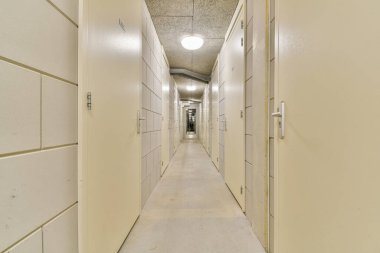 Uzun, aydınlık koridor beyaz depolama birimleriyle dolu verimli bir uzay kullanımı için ideal temiz ve düzenli bir ortam sunuyor..