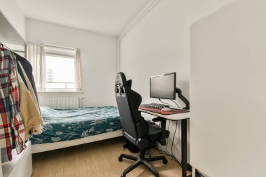 İçinde bilgisayar masası, ergonomik sandalye ve battaniyeli rahat bir yatak olan düzenli bir ofis. Oda parlak doğal ışık ve nötr renkler sergiliyor..