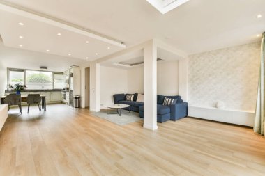 Çağdaş mobilyalar, ahşap döşemeler ve şık dekorasyon unsurlarıyla dolu parlak ve ferah bir oturma odası, rahatlama ve sosyalleşme için ideal..