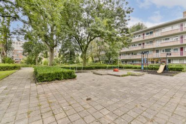 Bir şehir oyun alanı, canlı yeşil ağaçlar ve çalıların arasında kayar ve tırmanır, çocukların oynaması ve keşfetmesi için canlı bir açık alan yaratır..