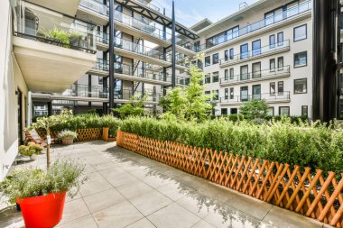 Zengin yeşillik ve şık ahşap çitlerle bezenmiş modern bir balkon kentsel bir ortamda huzurlu bir vaha yaratıyor..