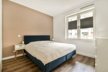 Basit bir dizaynı olan rahat bir yatak odası, ahşap döşeme ve doğal ışık arttırma için geniş bir pencere..