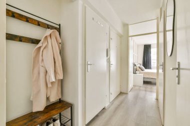 İyi tasarlanmış bir girişte basit bir palto askısı, modern bir dekor ve rahat bir yatak odasına açılan ahşap döşeme sergileniyor. Konfor ve tarzın bir karışımı çok açık..