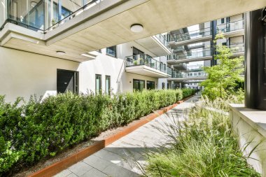 Çağdaş bir apartmanın davetkar bir manzarası, geniş balkonları ve yemyeşil bir bahçe yolu var..