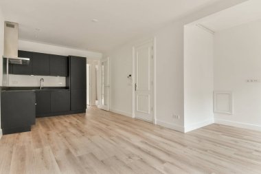 Siyah dolaplar, ahşap döşemeler ve çağdaş yaşam alanları için ideal minimalist tasarım elementlerinin yer aldığı gösterişli, modern bir mutfak..