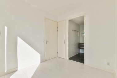 Parlak ve havadar bir atmosfere sahip geniş, minimalist bir iç mekan. Oda, şık bir banyoya açılan kapısı olan temiz hatları ve modern unsurları ön plana çıkarıyor..