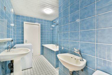 Mavi fayanslı duvarlar, beyaz eşyalar ve ferahlatıcı bir atmosfer için ideal bol ışıklandırmalı temiz ve çağdaş bir banyo..