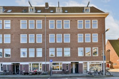 Modern mimari tasarım ve yüksek erişilebilirliği vurgulayan, kentsel bir ortamda geniş pencereler ve benzersiz bir cephe sergileyen çağdaş bir bina.