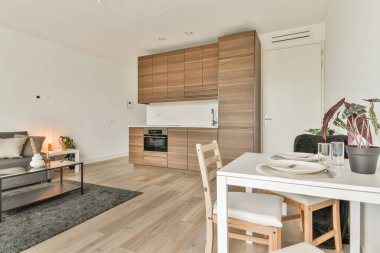 Çağdaş bir mutfak ve yemek odası. Minimalist mobilyalar, ahşap dolaplar. Basitlik ve zarafetin davetkar atmosferi..