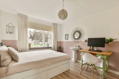 Güzel tasarlanmış modern bir yatak odası şık bir dekor, bir çalışma istasyonu ve büyük pencerelerden gelen doğal ışık..