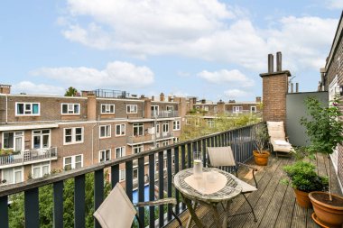 Açık hava mobilyalarının ve saksı bitkilerinin bulunduğu şık bir balkon, şehir manzarası ve temiz havanın keyfini çıkarmak için sakin bir alan sağlıyor..