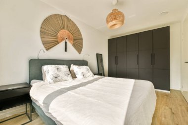 Lüks bir yatak odası, dekoratif duvar sanatı ve rahat bir atmosfer yaratan minimalist mobilyalar..