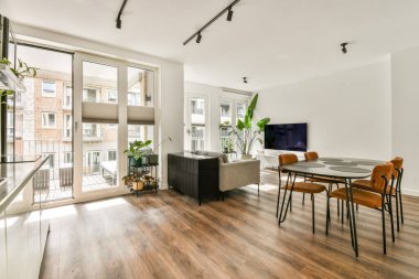 Geniş pencereli, parlak, modern bir oturma odası geniş doğal ışık, modern mobilyalar ve misafirperver bir atmosfer sunar..
