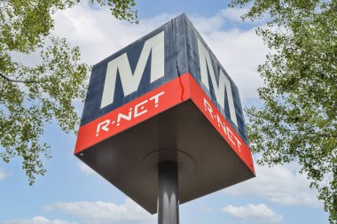 Belirgin bir R-NET işareti, yeşil yeşilliklerle çerçevelenmiş canlı mavi bir gökyüzüne karşı duruyor, modernlik ve berraklık hissi veriyor..