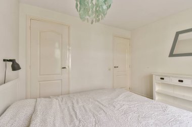 Beyaz bir paleti, minimalist mobilyaları ve şık bir tavan ışığı olan parlak ve havadar modern bir yatak odası. İç tasarım ilham kaynağı için ideal.