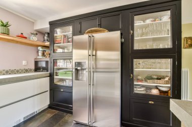 Paslanmaz çelik bir buzdolabı, şık bir dolap ve yemek pişirme alanını geliştiren zarif dekorlu düzenli bir düzen içeren çağdaş bir mutfak..