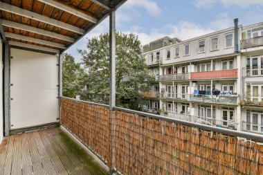 Yeşillik manzaralı balkonlu çağdaş bir apartman. Mimari modern tasarım elementlerini ve kentsel yaşamı yansıtır..