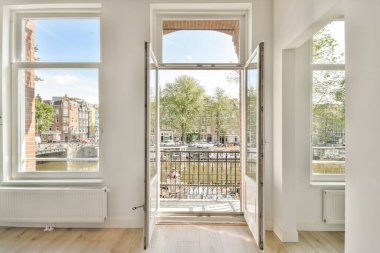 Geniş açık pencereli modern iç mekan yemyeşil ve suyun manzarasını sunuyor, sıcak ve davetkar bir atmosfer yaratıyor..