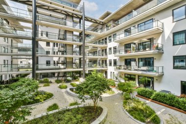 Bitki ve ağaçlarla dolu canlı bir avlusu olan çağdaş bir apartman kompleksi, şehir mimarisinin ortasında huzurlu bir yaşam alanı yaratıyor..