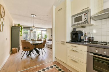 Modern aletler ve zarif dekorlarla şık bir yemek alanına kusursuz bir şekilde bağlı şık bir açık konsept mutfak. Ilık aydınlatma davetkar atmosferi güçlendirir.