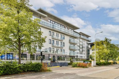 Çağdaş bir apartman kompleksi, bereketli ağaçlarla çevrili ve bakımlı bir peyzaj, sakin bir kentsel yaşam atmosferi yakalıyor..