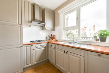 Pürüzsüz, modern mutfak vitrininde minimalist dolaplar, şık bir tezgah ve davetkar bir atmosfer yaratmak için geniş pencerelerden gelen geniş doğal ışık..