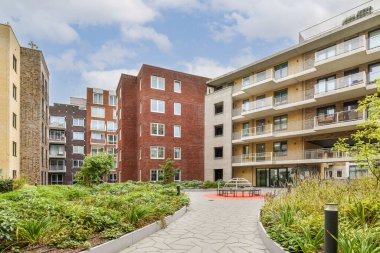 Yeşillik ve bakımlı yollarla çevrili çeşitli binaların bulunduğu çağdaş bir konut kompleksi, kentsel yaşamı ön plana çıkarıyor..