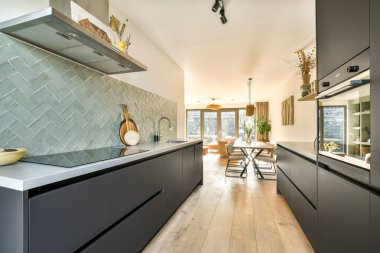 Zarif siyah dolaplar, zarif tezgahlar ve özenle düzenlenmiş yemek alanı, çağdaş tasarım ve işlevsellik içeren modern mutfak..