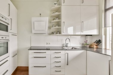 Minimalist dolapların, gösterişli tezgahların ve organize rafların yer aldığı modern bir mutfak, davetkar bir yemek alanı yaratıyor..