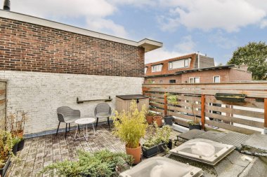 Modern mimari ile çevrili, rahatlama ve toplanma için mükemmel, saksı bitkilerinin ve rahat koltukların bulunduğu şık bir açık hava alanı..