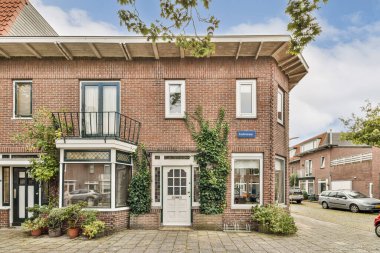 Yeşil bitkilerle süslenmiş güzel bir tuğla ev ve hoş geldin girişi. Çevrede tuhaf bir mahalle havası var..