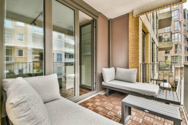 Modern bir balkon, modern konut mimarisinde rahatlama ve açık hava keyfi için tasarlanmış minimalist yastıklı minimalist mobilyalar içerir..