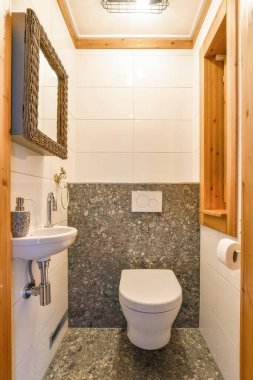 Tarafsız tonlarda, duvara monte edilmiş lavabo ve şık bir aynayla temiz bir tasarımı olan şık ve çağdaş bir banyo. Modern ev dekorunda ilham için ideal.
