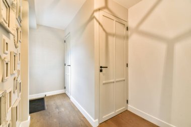 Tarafsız tonlarla, parlak ahşap zemin ve açık bir ortam oluşturan minimalist tasarım unsurlarının yer aldığı zarif ve modern bir koridor..