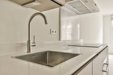 Gösterişli ve çağdaş bir mutfak, paslanmaz çelik aletler, minimalist bir tasarım, ve yemek pişirmek ve eğlendirmek için geniş bir tezgah..