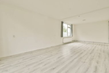 Beyaz duvarların olduğu boş bir oda, doğal ışık sağlayan büyük pencereler ve açık renkli döşemeler. Tasarım ilhamı ve minimalist estetik için ideal..