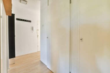 Parlak ve minimalist bir iç koridor. Temiz çizgiler ve ferahlık sergiliyor. Beyaz duvarlar ve çağdaş bir his için açık ahşap döşemeler var..