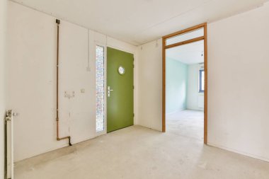Çarpıcı yeşil bir kapısı, minimalist duvarları ve geniş doğal ışığı olan çağdaş bir iç mekan. İç tasarım fikirlerini sergilemek için mükemmel..