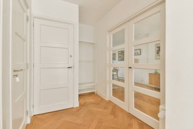 Beyaz kapıları ve ringa kemiği ahşap döşemeleri olan şık bir giriş. Parlak ve davetkar bir atmosfer yaratıyor..