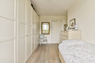 İyi tasarlanmış modern bir yatak odası, bir gardırop, çiçekli bir yatak, ve zarif bir dekor, sakin ve davetkar bir atmosfer yaratıyor..