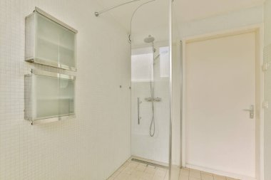 Pürüzsüz ve minimalist bir duş odası. İçinde cam duvarlar, modern eşyalar ve temiz döşeme döşemeleri var. Çağdaş yaşam alanları için mükemmel..