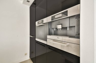 Gösterişli, çağdaş mutfak. Karanlık dolaplar ve minimalist tasarım. Aynalı kaplama, mekan ve estetiği optimize ediyor..